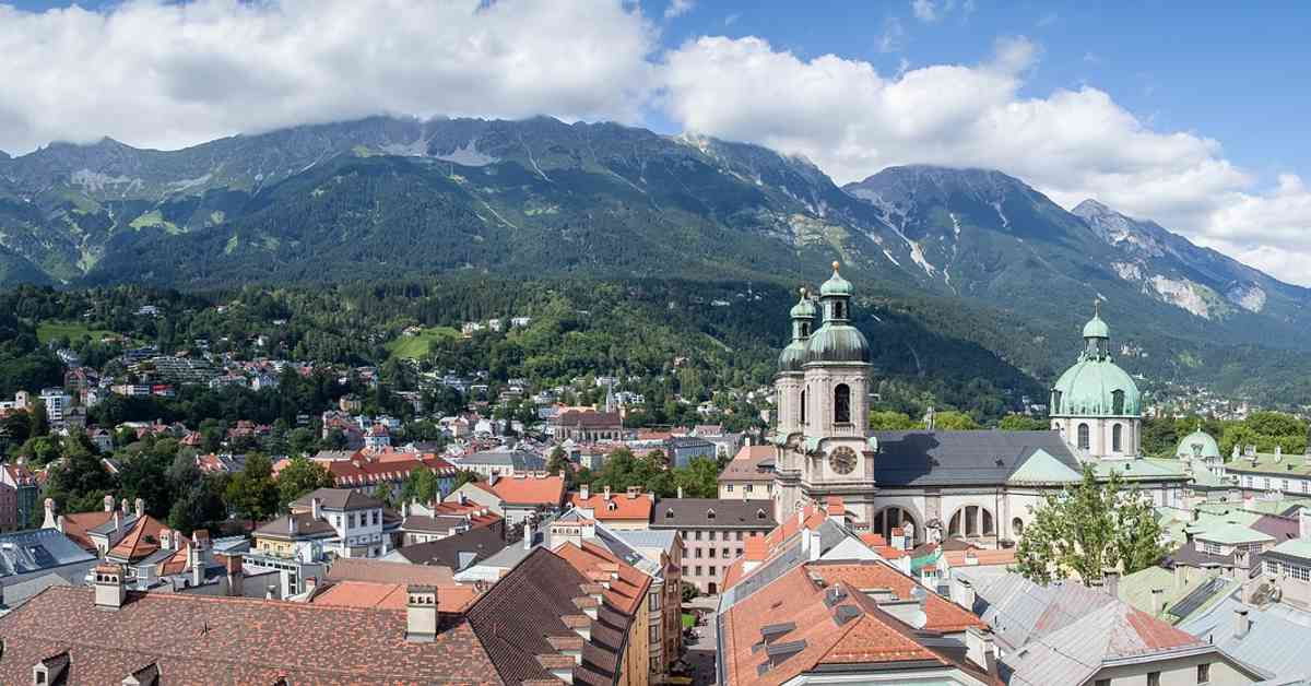 This is a landscape image of the perspective of buildings in Europe. Here we see a view of the terracotta roofs of Europe with the Alps in the background. We want to describe the Tourism Careers in this article By Cademix Institute of Technology, Cademix Magazine.